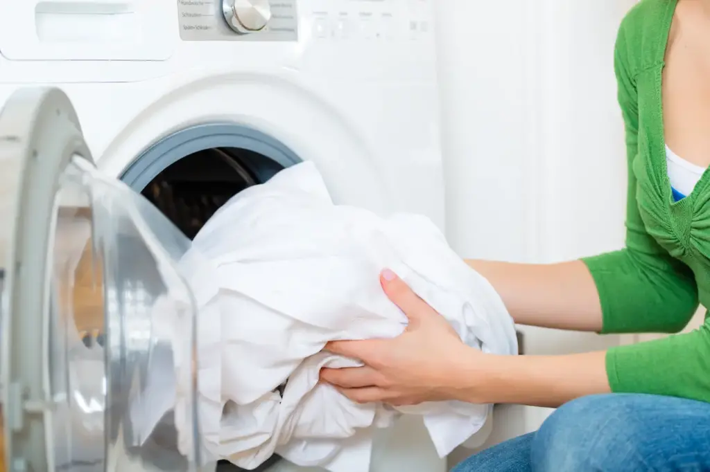 A Woman Takes The Laundry Out Of The Washing Machine, hat Is The Best Way To Wash Your Sheets?