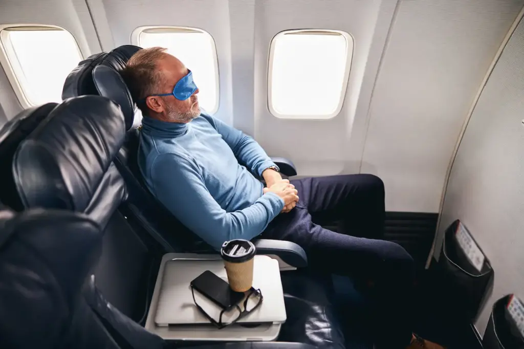 Man Sleeping on a Plane While Wearing A Blindfold, How To Fall Asleep On a Plane