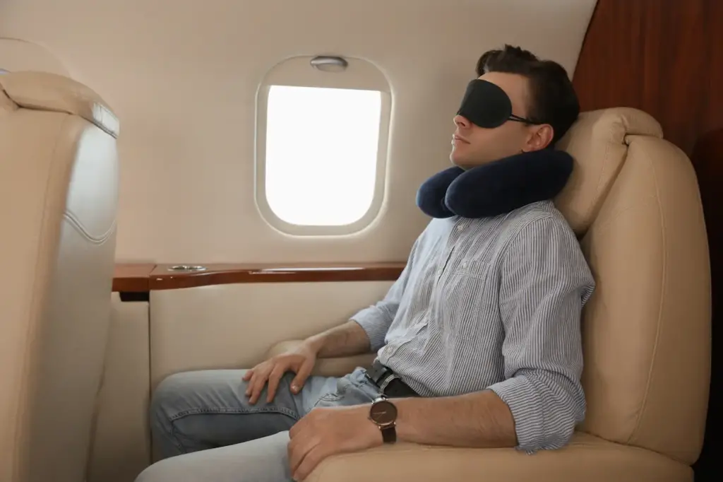 Man Sleeping With a Travel Pillow And Blindfold, How To Fall Asleep On a Plane?