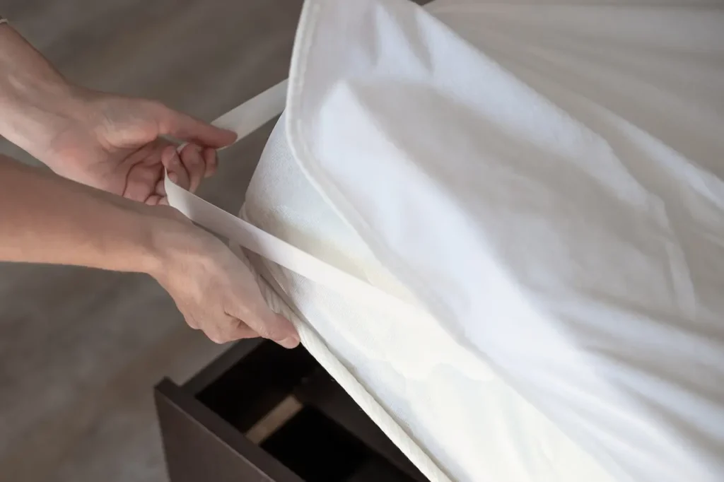 A Woman Puts a Mattress Topper on the Bed 