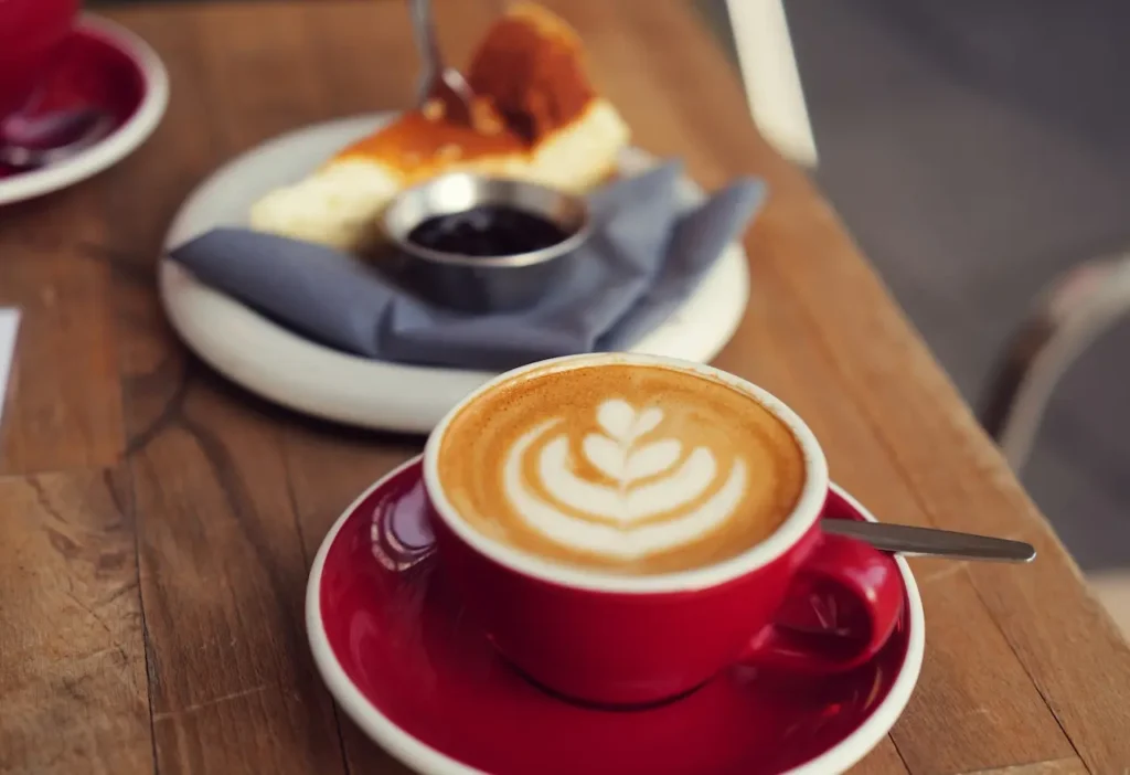 A Red Cup of Latte Art Coffee with Cheesecake 