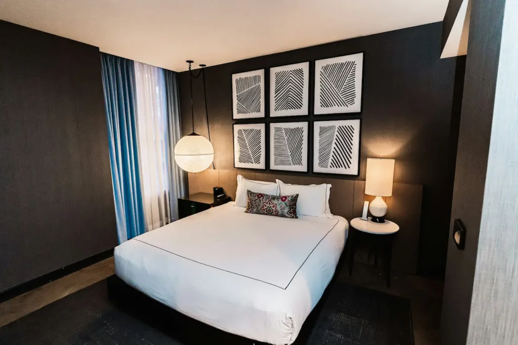 A White Bed with Paintings and Lamps in the Background