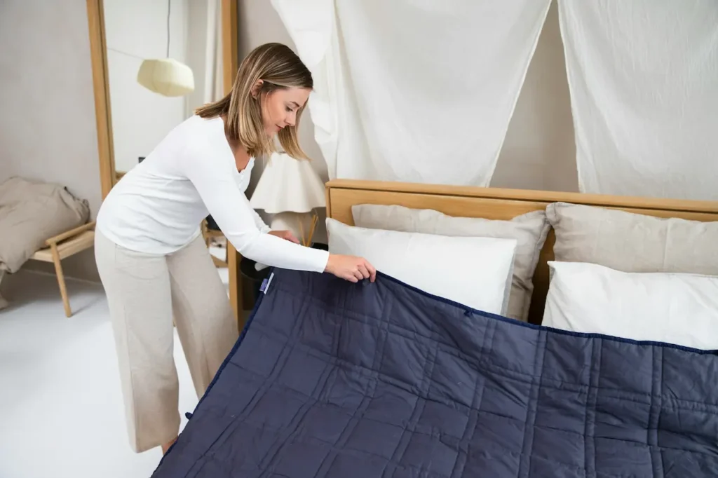 A Woman Placing a Blue Blanket on a Bed 