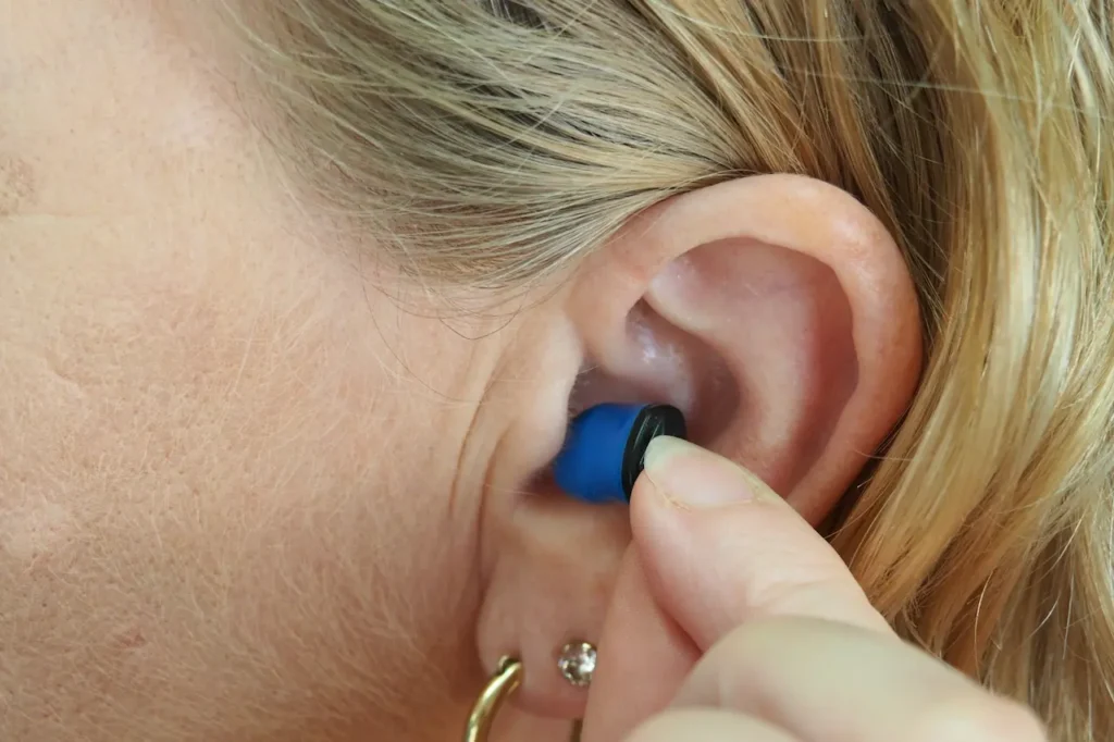 A Woman Putting Earplugs in Her Ears 
