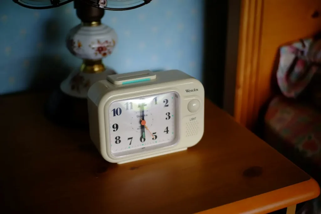 White Analog Clock Sitting on a Wooden Table